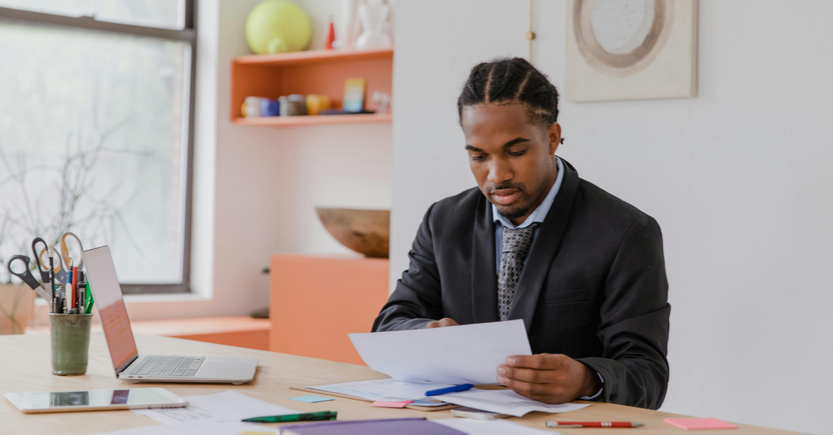 A small business owner overwhelmed with paperwork, representing the administrative burden of managing payroll and HR tasks internally.